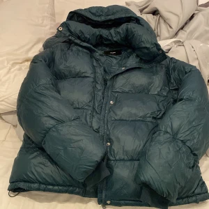 Mörkblå pufferjacka från BikBok - Säljer en mörkblå pufferjacka från BikBok i storlek M. Jackan har en rejäl huva, dragkedja och tryckknappar framtill. Perfekt för kalla dagar med sin fluffiga och vadderade design. Snygg och enkel att matcha med olika outfits. Pris kan diskuteras. OBS SKRIV INNAN NI KÖPER!