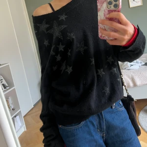 Svart stickad tröja med stjärnor Zadig & Voltaire - svart stickad tröja från Zadig & Voltaire med glittriga stjärnor framtill och kontrastfärgade röda muddar. 