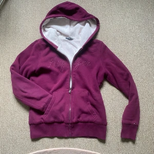 Isolerad päls hoodie - Så snygg och mysig vintage vinröd/lilarosa hoodie från Tommy Hilfiger! Broderad logga på bröstet och fodrad i hela tröjan🙌🏻Super varm och skön. Den har dragkedja, huva med vit fleecefoder och två fickor framtill. Väldigt sällsynt och populär! Perfekt för kyliga dagar och chill outfits💋Storlek S! Skriker y2k fur zip hoodie🤩Billigare på min Vinted: 4annie1. Pris kan diskuteras, hör av dig vid frågor!❤️