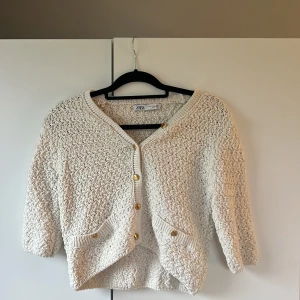Beige stickad kofta från Zara - Superfin beige stickad kofta från Zara med snygga guldknappar och två fickor fram. 