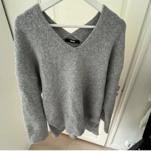 Grå stickad tröja från BikBok - Mysig grå stickad tröja från BikBok med v-ringad hals och breda ribbade muddar vid ärmslut och nederkant. 
