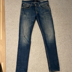 Blå Replay jeans, storlek 29/32 - Säljer ett par blå jeans från Replay i storlek 29/32.  slitningar och en smal passform. Skick 8/10