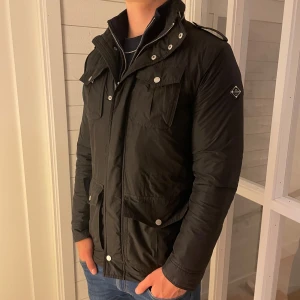 J Lindeberg jacka - Säljer denna riktigt snygga svarta field jacket från j lindeberg som är fodrad vilket gör den perfekt nu under hösten och även i vinter. Den har flera fickor på framsidan och även tre innerfickor. Jackan är i storlek S men sitter mer som M då den är lite stor i storleken. Den är i topp skick utan några defekter! Priset är inte hugget i sten så kom gärna med förslag! hör gärna av dig vid frågor!