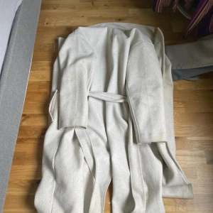 Ljusbeige kappa från Amisu, EU 40 orglinal pris 499 - Säljer en stilren ljusbeige kappa från Amisu i storlek 40. Kappan har klassisk krage, knytskärp i midjan och raka fickor. Perfekt för dig som vill ha en clean och enkel look till höst och vinter.