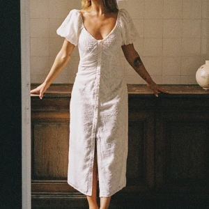 Vit midiklänning med puffärm - Vit midiklänning med puffärmar och knappdetalj. Sanna Jörnviks kollektion med NAKD.