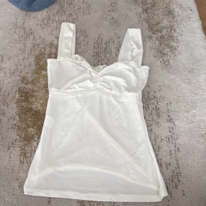 Vit linnetopp med spetsdetaljer - Jag säljer ett jätte fint linne från design by si💗 jag har aldrig använt❤️