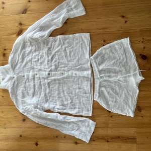 Vitt sett från hm - Vit, luftig skjorta i linne från H&M med lång ärm, bröstficka och knappar framtill. Perfekt för varma dagar med sin avslappnade passform och svala känsla. Säljes i set med matchande shorts.