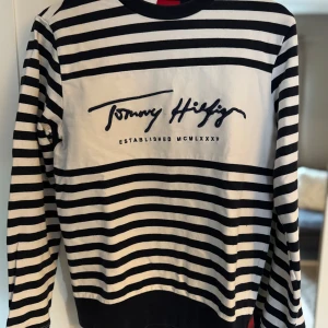 Randig tröja Tommy Hilfiger S - Långärmad tröja från Tommy Hilfiger i svart och vitt med breda ränder och broderad logga på bröstet. Tröjan ser ut att vara svart randing men är mörkblå egentligen 