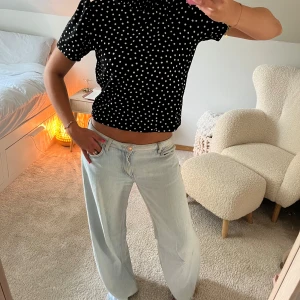 Svart prickig blus Zara - Supersöt svart blus med vita prickar och korta puffärmar. Modellen är croppad och har en lätt rynkad halsringning som ger en trendig look. Perfekt att styla med jeans eller kjol för en cool vibe.