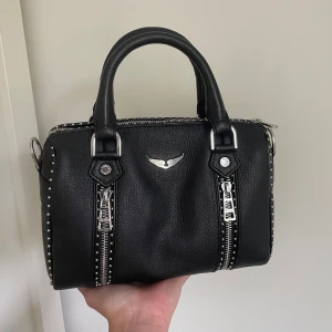 Zadig & Voltaire  - Säljer nu min superfina Zadig & Voltaire väska. Helt ny, men sitter inte kvar någon prislapp på eftersom jag använt den 2 gånger. Säljer pga att det finns annat jag är intresserad utav att köpa istället. Inga defekter eller liknande. Som ny 💞 Den är självklart äkta. Kvittot, äkthetsbevis samt dustbag finns och skickas även med vid köp. Viss prutmån finns, men inga orimliga bud. Köpt för 5100kr. Hör gärna av er 💞