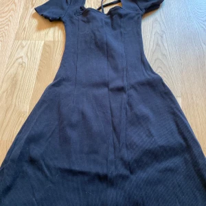 Svart ribbad kortklänning H&M Divided - Supersöt svart ribbad kortklänning från H&M Divided med korta ärmar och söt snörning vid bysten. Klänningen har en figurnära passform upptill och lätt utsvängd kjol. 