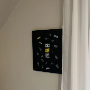 Grandsour tavla - det är en inramad NOCCO Focus burk med dekorativa element. 