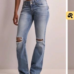 Nelly-Ljusblå bootcut jeans med slitningar - Snygga ljusblå jeans med bootcut passform och slitna detaljer över knäna. Hög midja med dubbla knappar och klassiska fickor bak med lock och knapp. Jeansen är i mjuk denim och har en trendig, avslappnad vibe.    Använda ca 3 gånger, köpte för 699kr