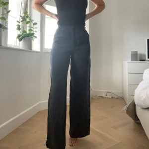 Svarta vida från Zara - Snygga svarta byxor från Zara med hög midja och vida ben. Byxorna har bälteshällor och klassisk stängning framtill. Använd fåtal gånger, fint skick. Storlek XS, men passar även S