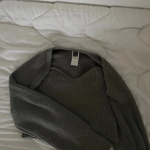 Grå ribbstickad tröja från SHEIN - Säljer en grå ribbstickad tröja från SHEIN med snygg sweetheart-urringning och långa ärmar. Tröjan har en croppad passform och är gjord i mjukt material som passar perfekt till lager-på-lager. Enkel att styla med både jeans och kjol. Helt oanvänd🥰