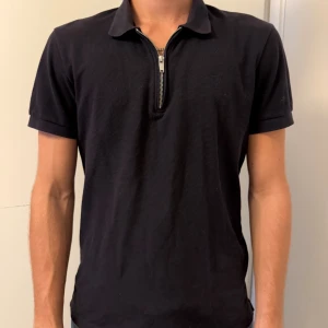 Mörkblå piké med zip från Jack & Jones - Mörkblå piké från Jack & Jones Premium med korta ärmar och krage. Snygg half zip-detalj framtill som ger en modern vibe. Tillverkad i mjuk bomull som känns skön mot huden. Passformen är normal och piken är stilren utan mönster.