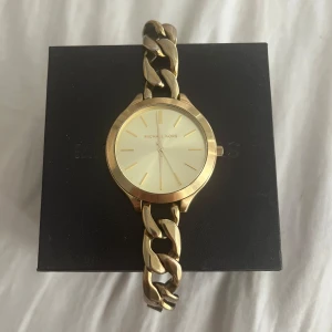 Guldig Michael Kors klocka MK-3222 - Snygg klocka från Michael Kors i modellen MK-3222. Klockan har en chunky länkarmband i guldtonad metall och en stilren urtavla i ljus färg med guldiga detaljer. Perfekt accessoar för dig som gillar statement-smycken och stilren design. Säljer för 1500kr, en helt ny kostar 2408kr! Skriv om ni har några frågor!😊💕