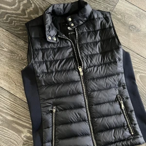 Marinblå väst från Zara Woman - Marinblå dunväst från Zara Woman med quiltad design och silvriga dragkedjor. 