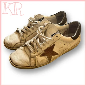 Golden Goose Pjuks  - Golden Goose sneakers i vitt skinn med brun mockastjärna på sidan och mörkbrun häl. Klassisk låg modell med snörning och rund tå. Snyggt slitna detaljer och retrovibe, perfekt för dig som gillar streetstyle och unika skor.