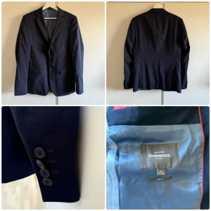 Mörkblå kostym från Dressmann - Säljer en stilren mörkblå kostym från Dressmann. En av knapparna på armen lite lös annars är den i bra skick. Kavajen är storlek 46R i slim fit och byxorna är 31/32 slim fit. En slips följer med på köpet också. 