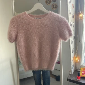Rosa fluffig tröja från Zara - Säljer en supermjuk och fluffig rosa tröja från Zara. Den har korta ärmar och en rund halsringning, perfekt för en mysig look. Tröjan är en M men sitter som S.nästan alldrig använd och inga deferenser