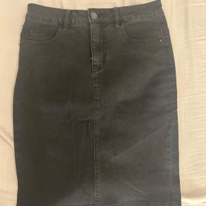 Svart jeanskjol från Vero Moda - Snygg svart jeanskjol från Vero Moda i storlek S. Kjolen har slits baktill.
