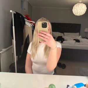 Vit topp med öppen rygg - Säljer en stilren vit topp med öppen rygg. Toppen har korta ärmar och en tight passform, perfekt för en trendig look. Passar bra till både jeans och kjol.