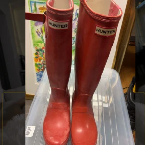 Röda stövlar från Hunter - Snygga röda/orange stövlar från Hunter. Höga med ett knäppe på sidan. Missfärgade-Vit fläckiga i färgen.