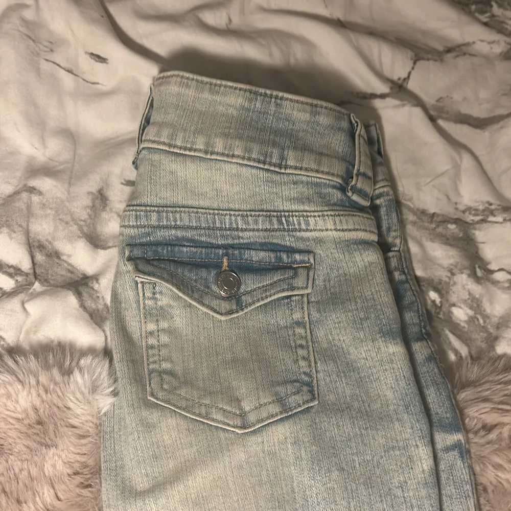 Säljer ett par ljusblå bootcut jeans från H&M. De har en justerbar midja och är lågmidjade. Perfekta för en avslappnad stil med en klassisk tvätt. De är i helt nyskick men ej prislapp kvar . Farkut & Housut.