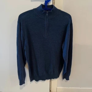 Blå tröja med dragkedja från Long Island - Snygg blå tröja från Long Island med halv dragkedja och ribbad krage. Perfekt för kyligare dagar med sin stilrena design och långa ärmar. Passar bra till både jeans och chinos. De var i storlek xl men krympte i tvätten och sitter därmed nu som en M