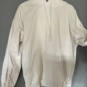 Vit hoodie med ficka - Säljer en stilren vit hoodie med känguruficka och justerbar huva. Perfekt för en avslappnad look. Passar till många olika tillfällen.