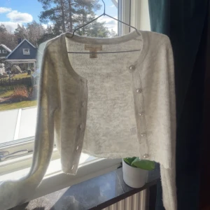 Vit kofta från Happily Grey - Säljer en stilren vit kofta från Happily Grey. Koftan har långa ärmar och knäpps med dekorativa knappar framtill. Perfekt för lager-på-lager under kyliga dagar. 🧥✨ Lappen är inte smutsig utan den ser ut så 🤍
