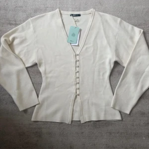 Vit kofta från Gina  - Snygg vit kofta från Gina med v-ringning och knappar framtill. Använd endast en gång. Inga defekter eller tecken på användning. 🫶🏻