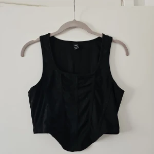 Svart korsett från Shein - Snygg svart korsett från Shein i en stilren design. Den är ärmlös och har en tight passform som framhäver figuren. Perfekt för att skapa en trendig look.