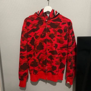 Röd Bape zip hoodie - Säljer en  röd Bape hoodie som knappt är använd. Köpt nyligen men ångrar mig. Inge defekter eller något. Storlek M  Pris kan diskuteras i snabba kassa. Kontanta för mer frågor osv