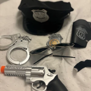 Svart polisuniform  - Snygg svart polisuniform hatt med silverfärgad polisbricka framtill med mera. Perfekt för maskerad, halloween eller temafest. (Allt på bilden kommer med i ett skick) helt nytt 