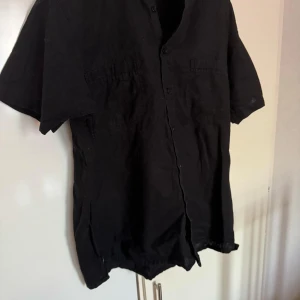  Battistini - Säljer en svart kortärmad skjorta från Battistini. Skjortan har knappar framtill och en klassisk krage. Perfekt för en stilren look.