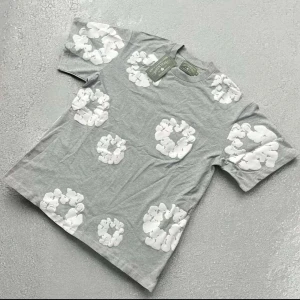 Denim tears summer set - Säljer ett par grå shorts från Denim Tears med ett coolt vitt blommönster. Shortsen har en bekväm resårmidja med snörning för perfekt passform. Perfekta för en avslappnad stil!