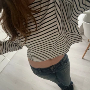 Randig croppad tröja - Säljer en stilren randig croppad tröja med svartvita ränder. Tröjan har trekvartsärmar och en lös passform, perfekt för en avslappnad look.💗💗