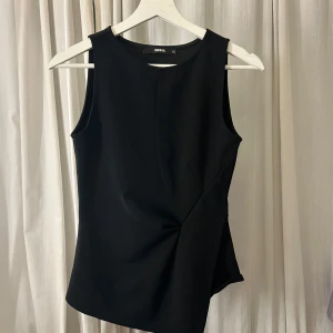 Svart ärmlös topp - Snygg svart ärmlös topp från bikbok. Tillverkad i ett mjukt och bekvämt material som ger en elegant passform. Använd 1 gång.