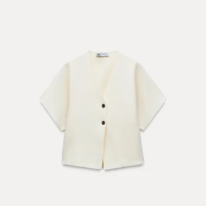 Vit v-ringad topp från Zara - Säljer en stilren vit topp från Zara med v-ringning och knappar framtill. Perfekt för att lägga till en touch av elegans till din outfit.