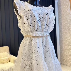 Vit klänning med broderade detaljer - Charmig vit klänning med broderade detaljer och volanger. Klänningen har en elastisk midja och en liten öppning i ryggen. Perfekt för sommarens alla tillfällen! Passar perfekt som oversize modell (s/m/l storlek). 👌🌸
