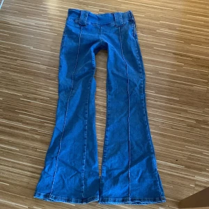 Blå bootcut jeans - Snygga blå bootcut jeans med låg midja och dragkedja på sidan. Perfekta för en avslappnad stil med en modern touch. De har en klassisk jeanslook med en twist.