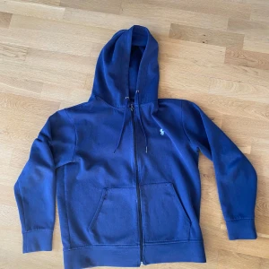 Ralph lauren zip hoodie  - Säljer en snygg blå hoodie från Polo Ralph Lauren. Den har defekter och små hål och det märks att den är använd. skriv för bilder på defekterna. Priset är inte hugget i sten. Mvh 