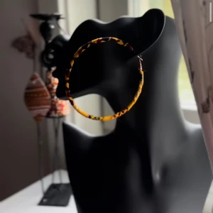 Stora leopardmönstrade hoops från Shop with Tyra - Säljer ett par stora hoops-örhängen med leopardmönster i gult, gul och svart. Örhängena har en snygg tygklädd yta som ger en unik och trendig look. Perfekta för dig som vill sticka ut och addera färg till din outfit. Följ oss på Instagram; @shop_with_tyra