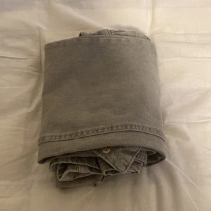 Grå cargopants med fickor - Snygga grå cargopants från Gina Tricot med hög midja och flera praktiska fickor, inklusive en stor ficka med lock och knapp på benet. Jeanskänsla i materialet och dubbla knappar i midjan. Perfekta för en avslappnad och trendig look.