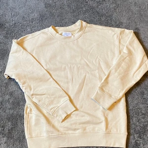Beige crewneck från Studio Total - Snygg beige crewneck från Studio Total i 100% bomull. Tröjan har klassisk rund halsringning, långa ärmar och en relaxed passform. Perfekt att slänga på sig för en chill look. Enkel och stilren design som funkar till det mesta.