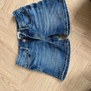 Blå jeansshorts från 157, stl 130 - Klassiska blå jeansshorts från 157 med normal passform. Shortsen har fem fickor, bälteshällor och knapp- samt dragkedjestängning. Snyggt tvättad denim med kontrastsömmar och raka ben. Perfekta för sommardagar och enkel att matcha med allt.