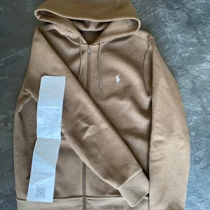 Polo Ralph Lauren Hoodie - Jätte fin Ralph Lauren Hoodie i färgen brun/beige. Använd endast en hand full gånger och är i storlek S. Kvitto finns! Vid några fundering är det bara att höra av sig! /Alex