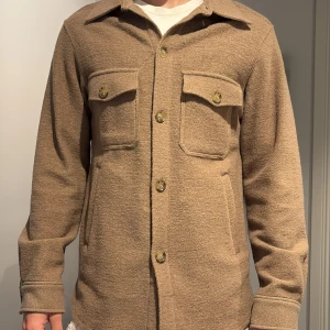 Beige overshirt från Oscar Jacobson - Snygg beige overshirt från Oscar Jacobson i ullmix. Nypris: 3299kr! Helt oanvänd 
